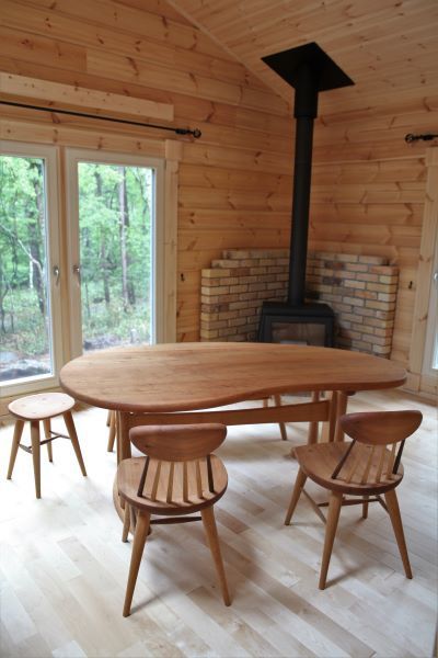 別荘に置かれたそら豆形のダイニングテーブルと木の椅子とスツール